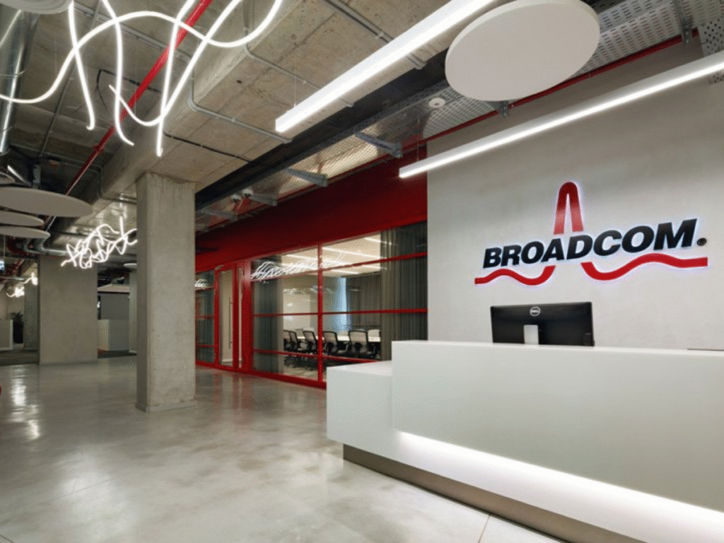 Interior view of a modern Broadcom office with a reception desk, company logo, glass meeting rooms and contemporary ceiling lighting.