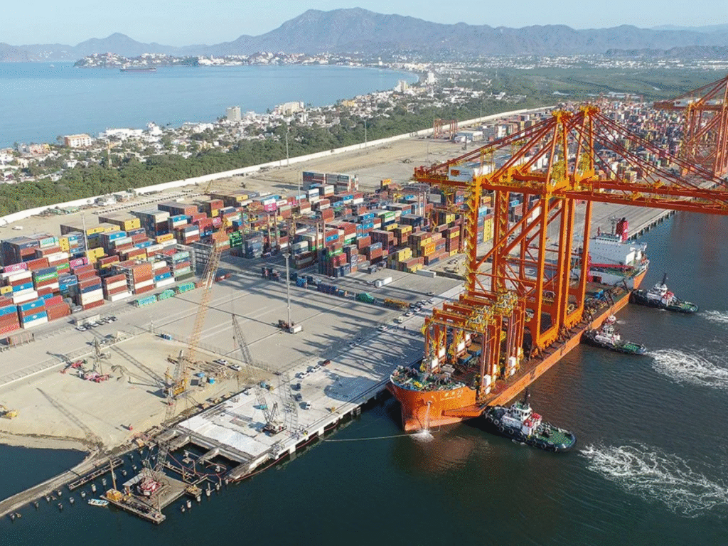 Aerial view of Manzanillo seaport in Mexico showing container ships, cranes, and cargo operations.