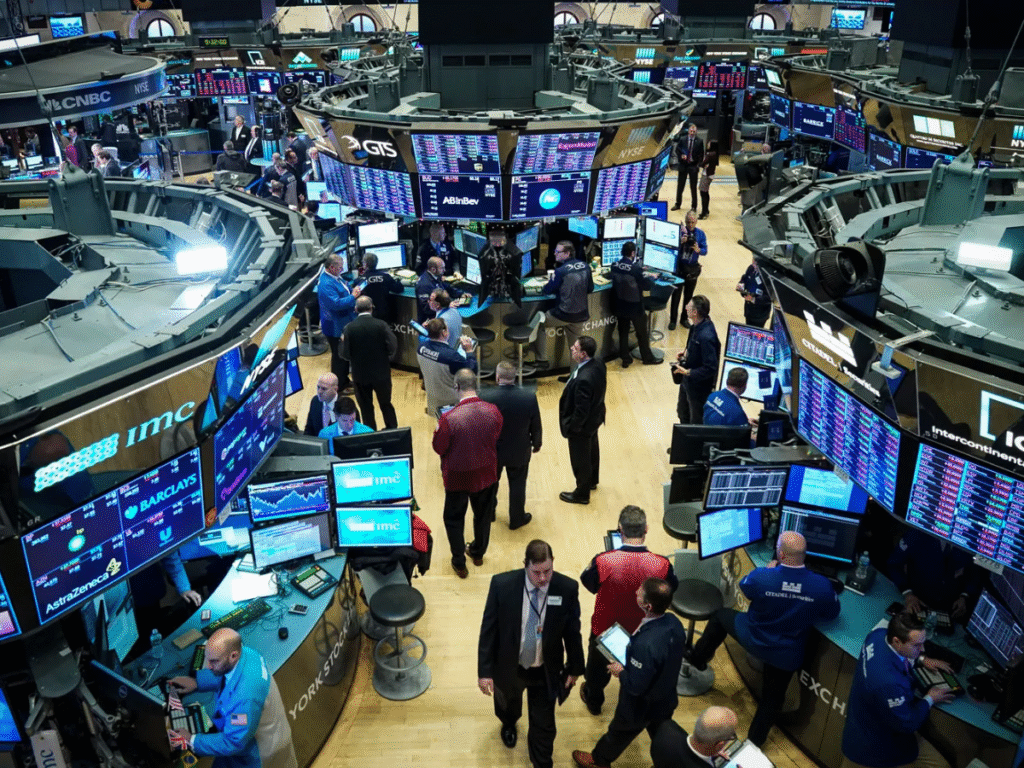 Traders and analysts work on the floor of the New York Stock Exchange, with multiple digital screens displaying market data and stock prices